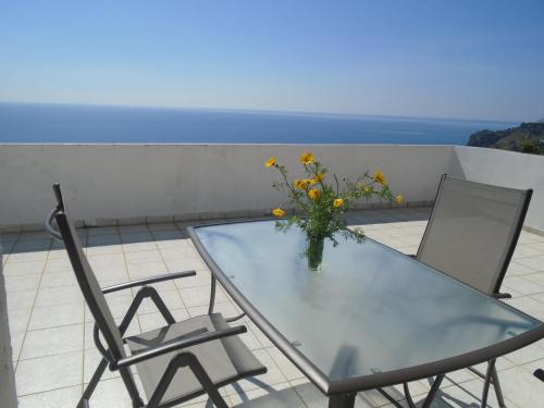 a glass table with two chairs and a vase of flowers at Giota & Antonia Apartments in Koroni