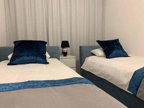 two beds with blue pillows in a bedroom at Apartament Zacisze De LUX in Malbork