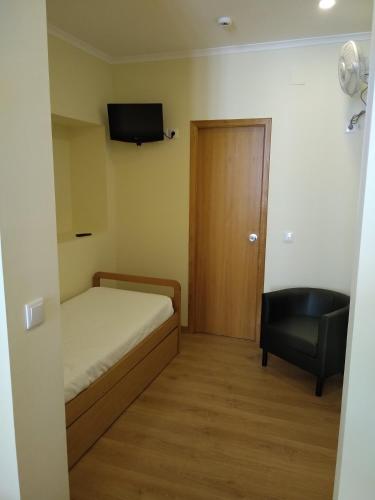 a small room with a bed and a chair and a television at Pensao Estacao Central in Lisbon