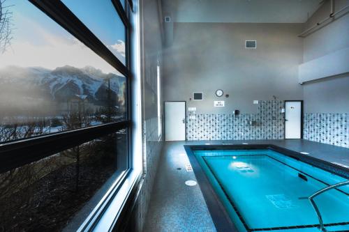 Super 8 by Wyndham Canmore في كانمور: حمام به مسبح بجانب نافذه