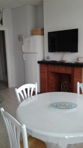 - une table et des chaises blanches dans une cuisine avec une télévision dans l'établissement 10 Quai François 1er, au Tréport