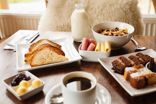 纳塔列斯港Hostal Boutique Factoria Patagonia的桌子上摆着几盘食物和一杯咖啡