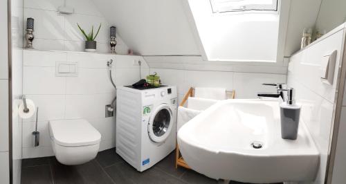 a white bathroom with a washing machine and a sink at Casa Muro in Friedrichshafen