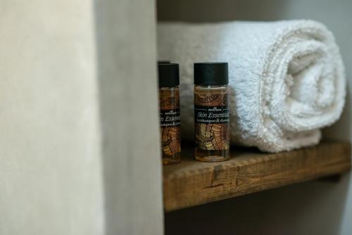 two bottles of essential oils on a shelf next to a towel at Kallisti Studios & Apartments in Skiros