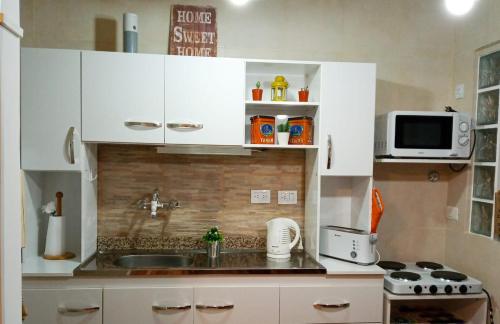 cocina con armarios blancos, fregadero y microondas en Apartamento Buenos Aires en Buenos Aires
