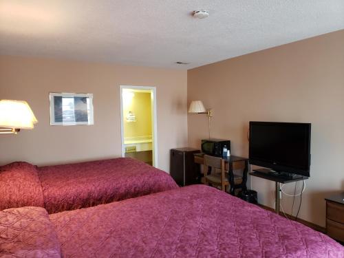 a hotel room with a bed and a flat screen tv at Town'n Country Motor Inn in Leamington