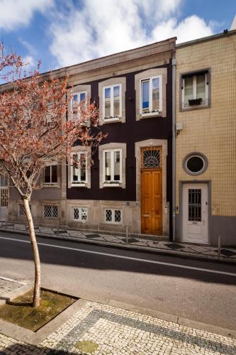 a building with a tree in front of a street at Fishtail Sea House in Matosinhos