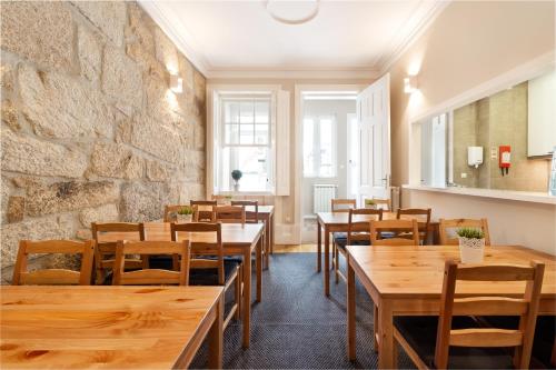a restaurant with wooden tables and chairs and a stone wall at Fishtail Sea House in Matosinhos