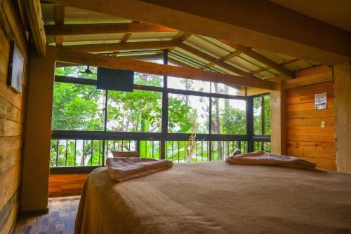 a bedroom with a large bed with a large window at Rancho Tierra Alta in Jarabacoa