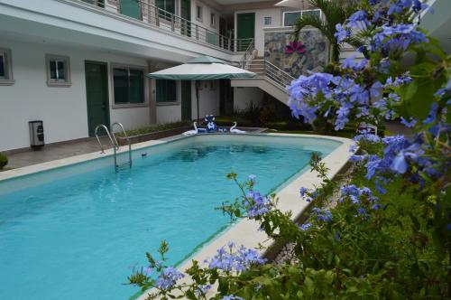 a swimming pool with blue flowers next to a building at hotel villa magna poza rica in Poza Rica de Hidalgo