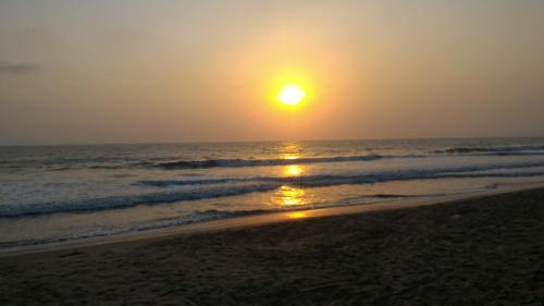 a sunset on a beach with the ocean at Sun n Tan Beach Home stay in Kannur