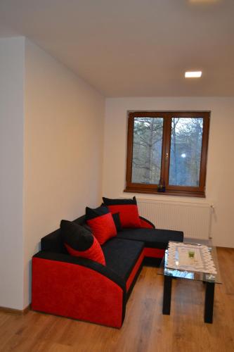 a living room with a red couch and a table at Chata Colonada in Valča