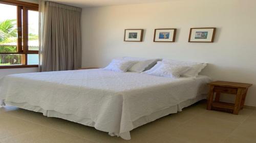 a bedroom with a large white bed with two pillows at Casa de praia na Costa do Sauípe in Costa do Sauipe