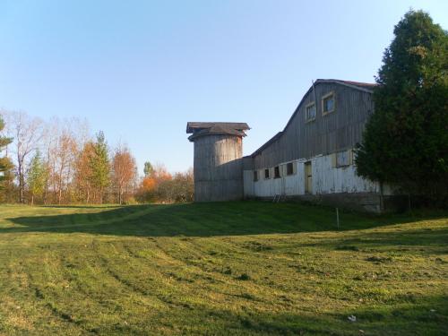 an old barn with a silo on a grass field at Auberge de la Tour et Spa in Magog-Orford