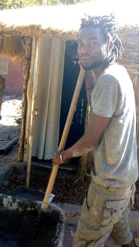 a man holding a stick in a bucket at Chez Bethy Jungle et Océan in Abene