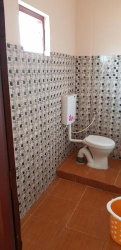 a bathroom with a toilet and a window at Hotel Nuhman in Kondotti