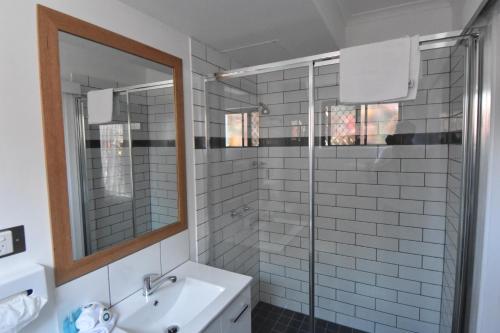 a bathroom with a sink and a glass shower at Ballina Homestead Motel in Ballina