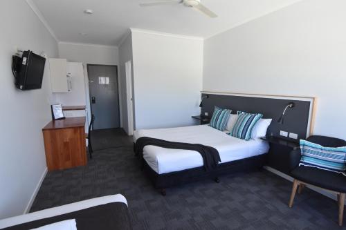 a bedroom with a bed and a desk and a chair at Ballina Homestead Motel in Ballina