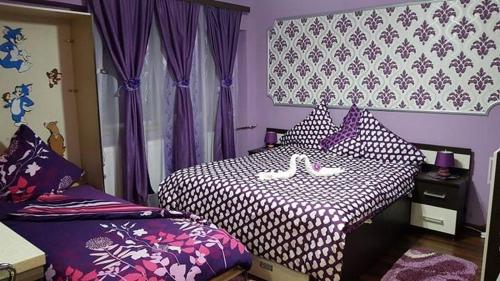 1 dormitorio con cama blanca y negra y cortinas moradas en Garsoniera Cristina, en Băile Felix