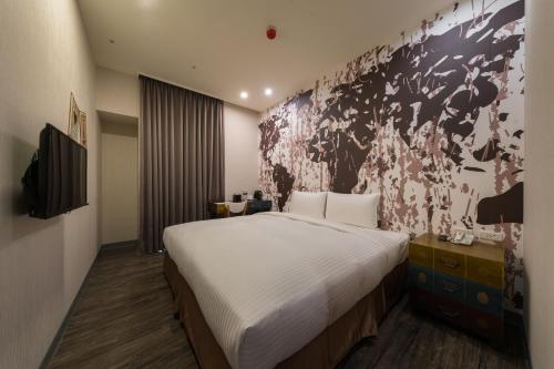 a bedroom with a large bed and a wall mural at Skyone Hotel in Kaohsiung