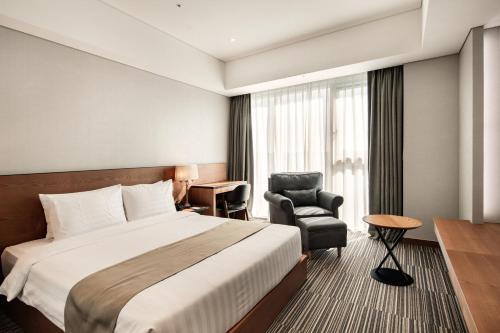 a hotel room with a bed and a chair at Golden Tulip Incheon Airport Hotel in Incheon