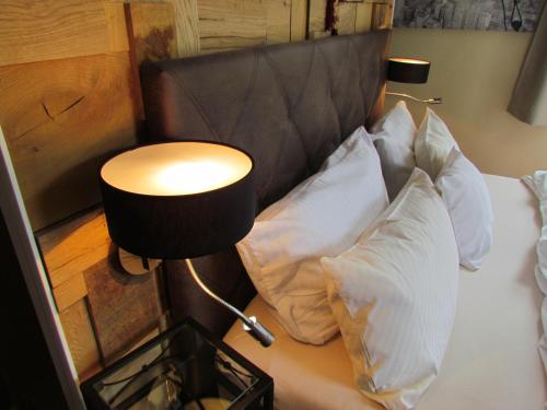 a bed with white pillows and a table with a lamp at Hotel Almrausch in Bad Reichenhall