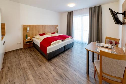 Pokój hotelowy z łóżkiem, stołem i biurkiem w obiekcie Boardinghaus Bayerwaldpark w mieście Landshut