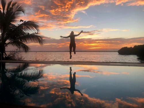 a woman jumping into the water in front of a pool at Nico Lagoon Hotel in Negombo