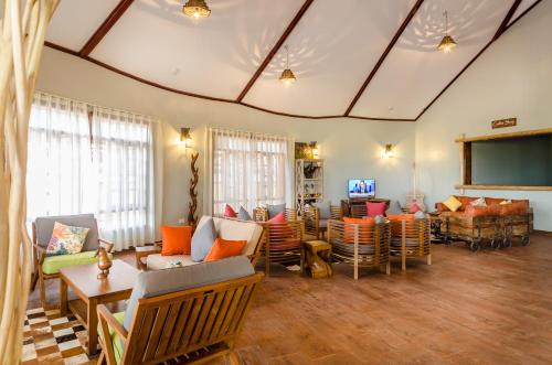 a living room with couches and chairs and a flat screen tv at Emburara Farm Lodge in Mbarara