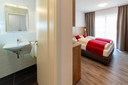 łazienka z łóżkiem i umywalką w pokoju w obiekcie Boardinghaus Bayerwaldpark w mieście Landshut