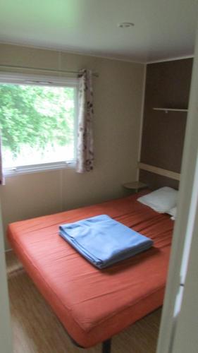 1 dormitorio con cama roja y ventana en Mobil Home 3 ch, en Saint-Georges-de-Didonne