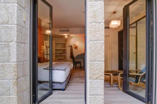 a bedroom with glass doors leading to a bed at Jacuzzi & Secret Garden in David's Village by FeelHome in Jerusalem