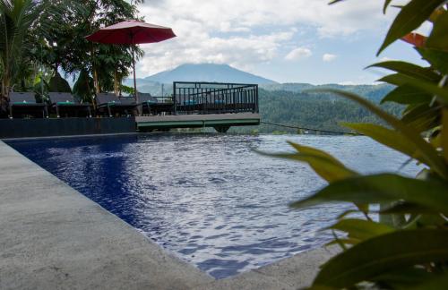 a swimming pool with a table and an umbrella at Bali Rahayu Homestay in Munduk