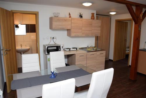 a kitchen with a table and white chairs in it at Penzion Zátiší in Komorní Lhotka