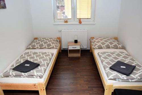 two beds in a room with a table and a window at Penzion Zátiší in Komorní Lhotka