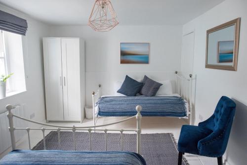ein Schlafzimmer mit einem Bett und einem blauen Stuhl in der Unterkunft Pebbles in Lyme Regis