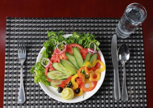 un plato de comida con frutas y hortalizas en una mesa en Alazhar Palace Hotel, en Al Qunfudhah