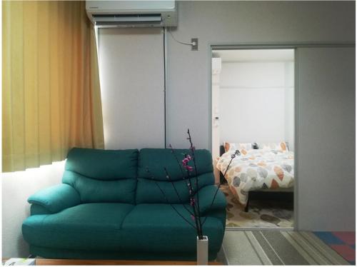 een woonkamer met een groene bank en een bed bij NEBULA K in Kumagaya