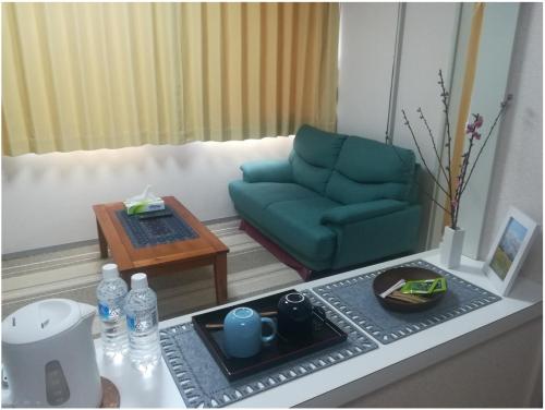 a living room with a green couch and a coffee table at NEBULA K in Kumagaya