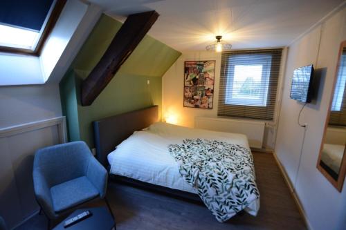 een kleine slaapkamer met een bed en een blauwe stoel bij Hotel De Beukelaer in Roggel