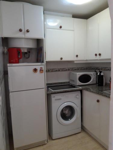 cocina pequeña con armarios blancos y lavadora en Apartment Manuel Galián 52, en Torrevieja