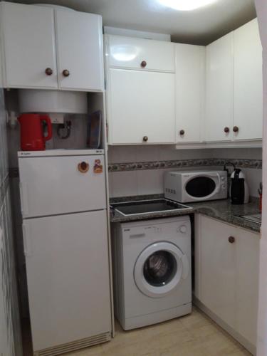 małą kuchnię z białymi szafkami i pralką w obiekcie Apartment Manuel Galián 52 w mieście Torrevieja