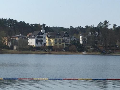 a boat in the water with houses in the background at Röblinseeterrassen in Fürstenberg-Havel