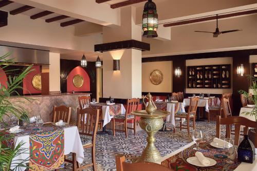 a restaurant with tables and chairs in a room at JAZ Lamaya Resort in Coraya Bay