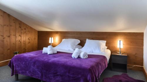um quarto com uma cama com lençóis roxos e almofadas brancas em Appartement Le Caboen Les Planards em Chamonix-Mont-Blanc