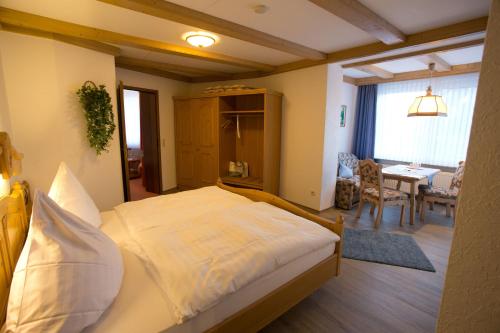 a bedroom with a large bed and a dining room at Landhotel Teuteberg in Bad Arolsen