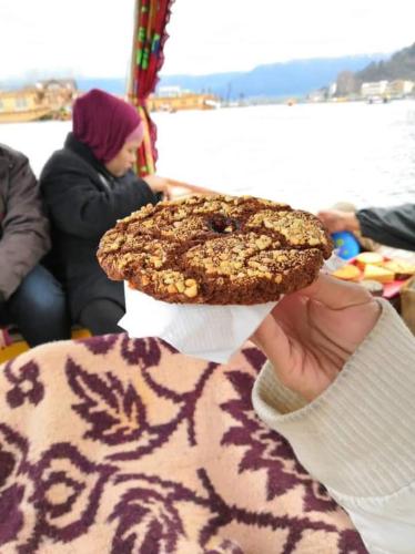 a person holding up a cookie on top at Houseboat New Suzan in Srinagar