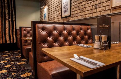 a table in a restaurant with a leather booth at The Coachman Hotel in Kilsyth