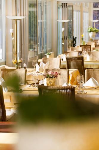 a restaurant with a long table with chairs and wine glasses at Parkhotel Tristachersee in Lienz