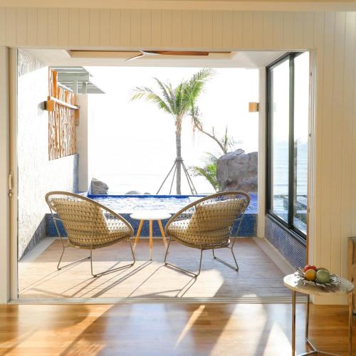 a patio with two chairs and a table with a view of the ocean at Kundala Beach Resort Hua Hin in Hua Hin